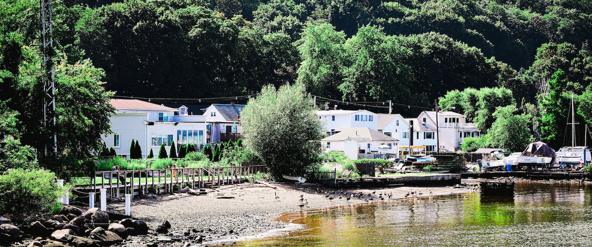 A riverside town with houses, a wooden bridge, and boats.