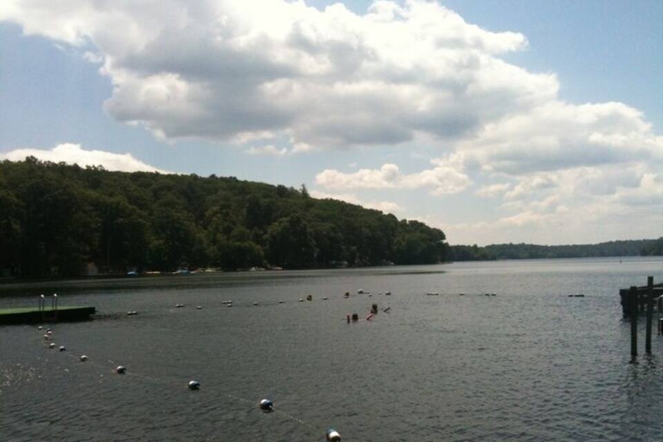 A calm lake with buoys, a dock, and a forested shoreline.