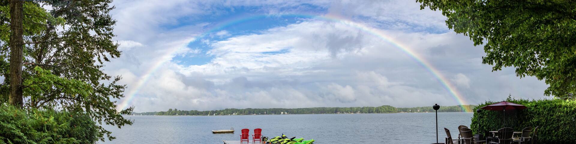 Panoramic full rainbow over the dock at the lake