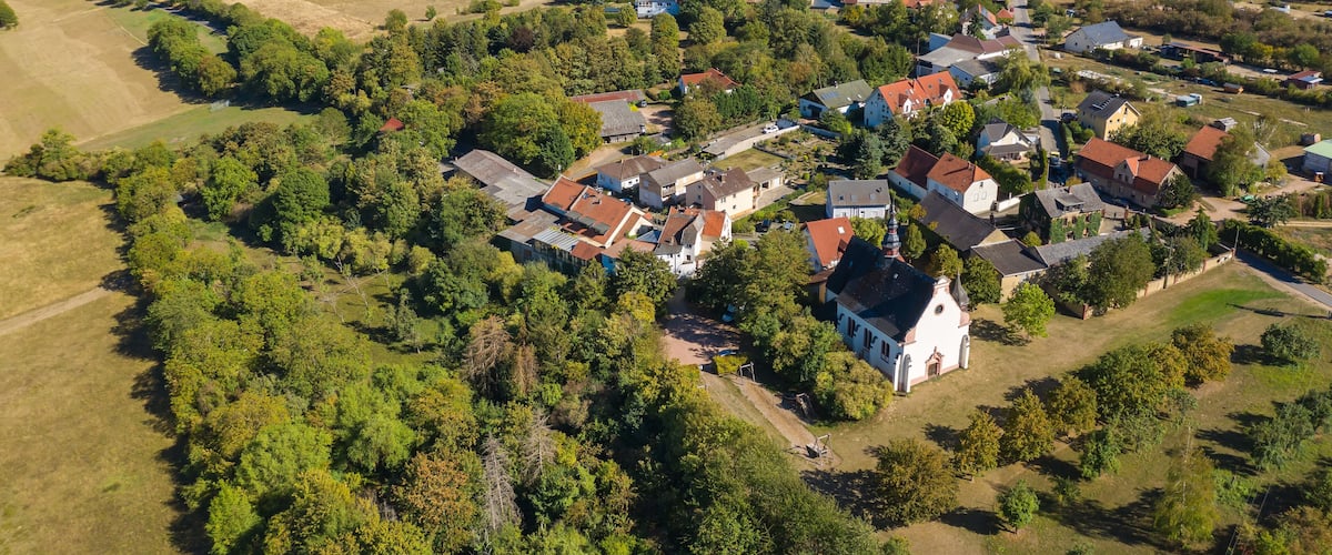 An aerial view of a rural village with houses, fields, and a church.
