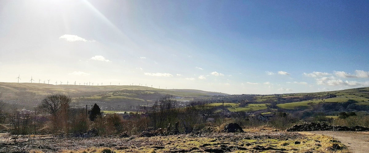 A rural landscape with wind turbines, rolling hills, and a clear sky.