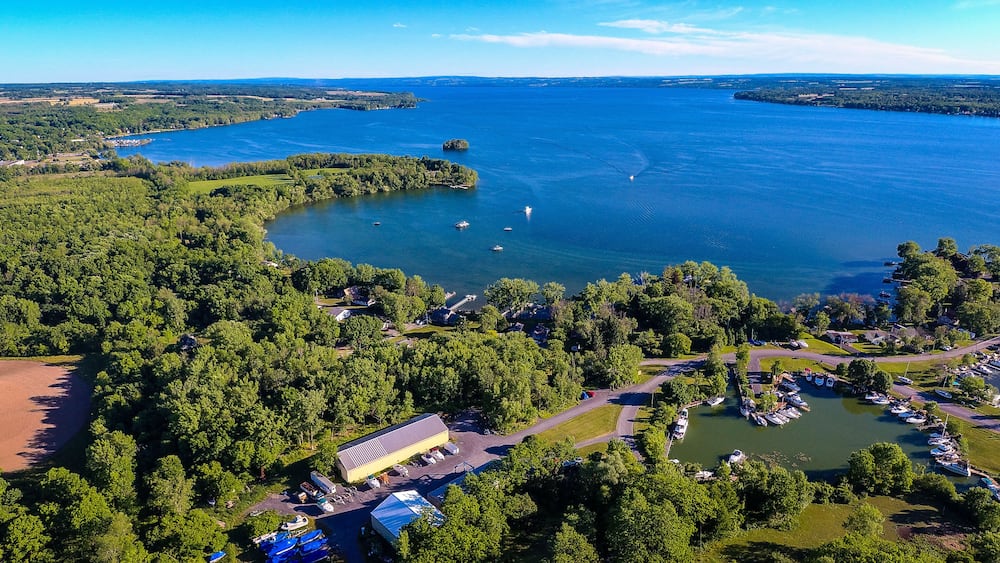 An aerial view of a lake surrounded by dense forests and a marina with boats.
