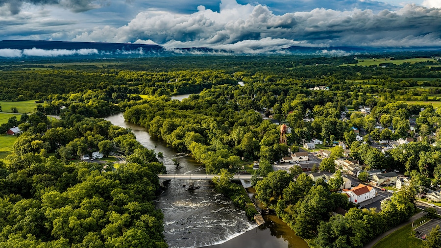 A river winding through a densely wooded area with a bridge and a small town.
