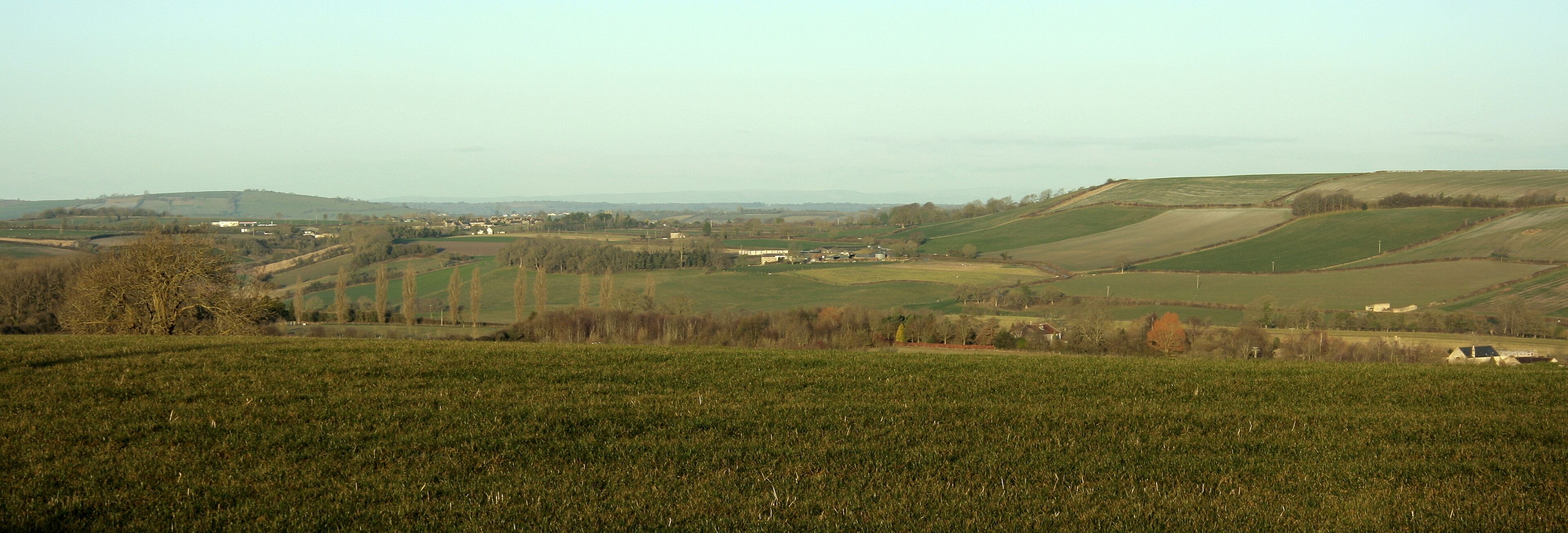 Rolling hills, fields, and scattered houses in a rural landscape.