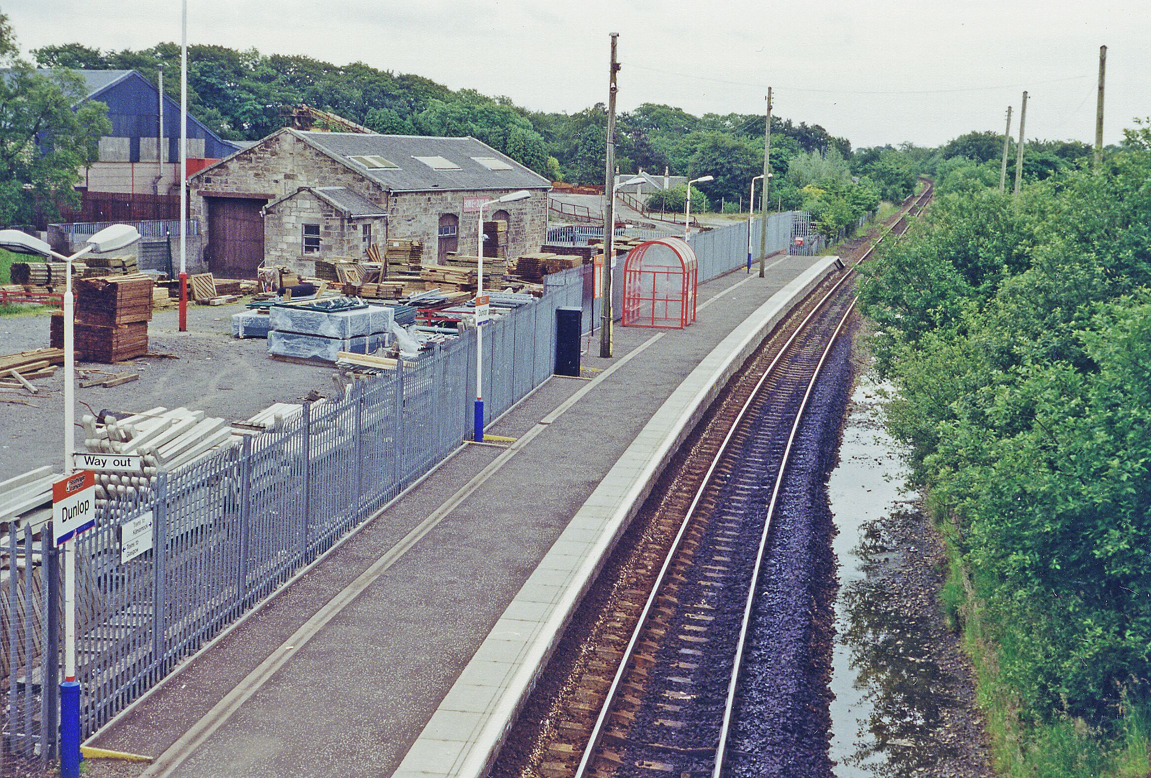 Dunlop station, 1996. View southward, towards Kilmarnock, Dumfries and Carlisle: ex-Caledonian & GSW (Glasgow, Barrhead & Kilmarnock) section of the Glasgow - Kilmarnock - Dumfries - Carlisle main line. The station was closed 11/66-6/67 and the line singled in 1975, but doubled again in 2009.