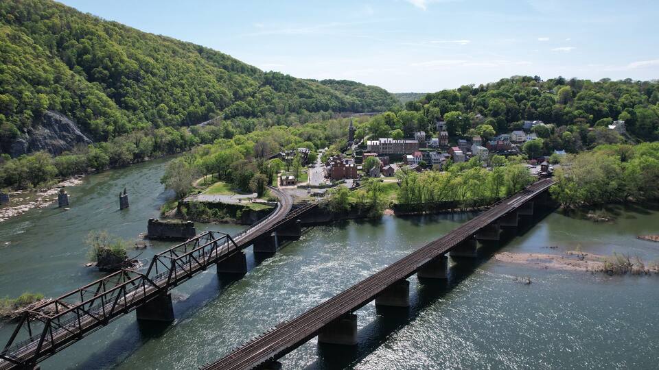 A river with a bridge, a town, and a forested hill.