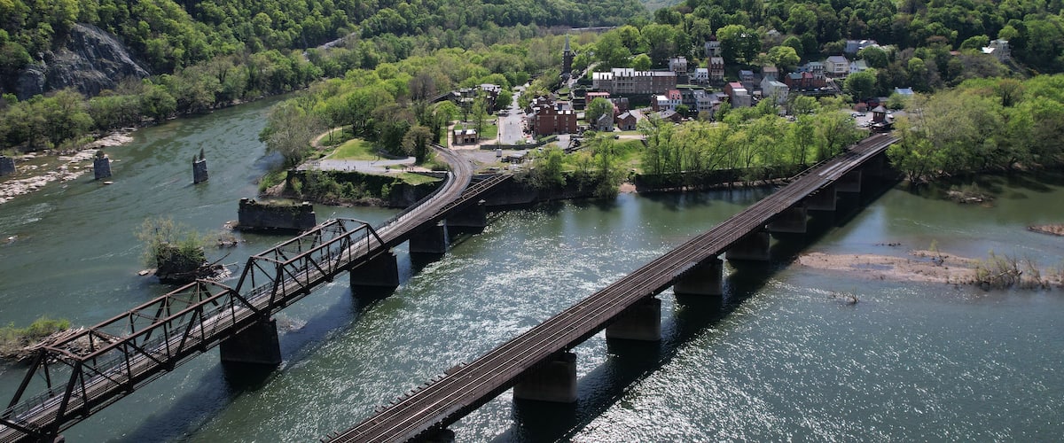 A river with a bridge, a town, and a forested hill.