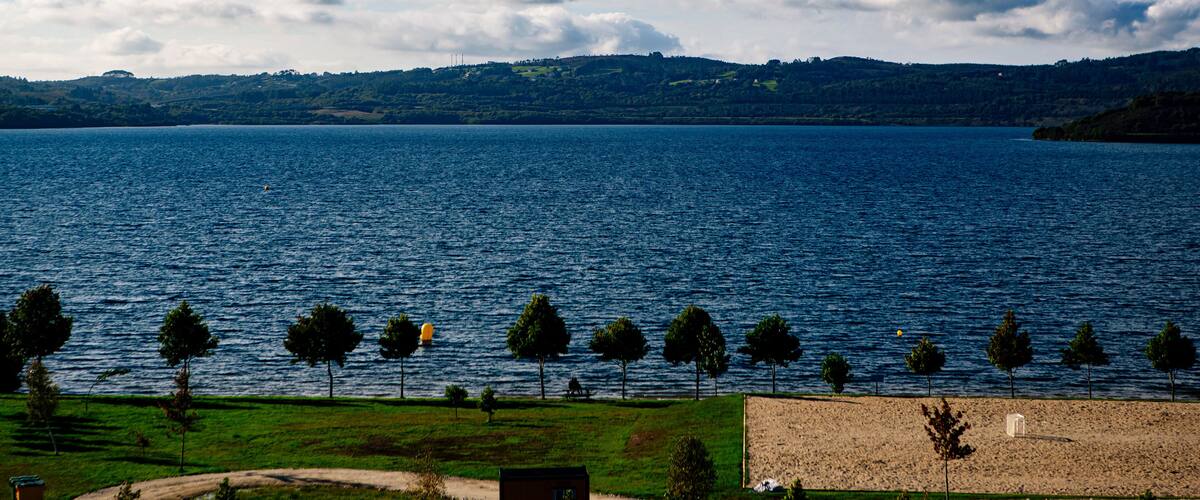 A lake with a clear sky, trees, and distant hills.