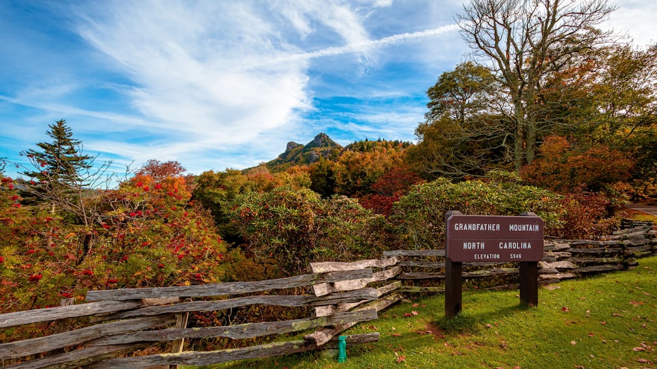A wooden fence, a sign reading "Grandfather Mountain, North Carolina, Elevation 5946", and autumn-colored trees.