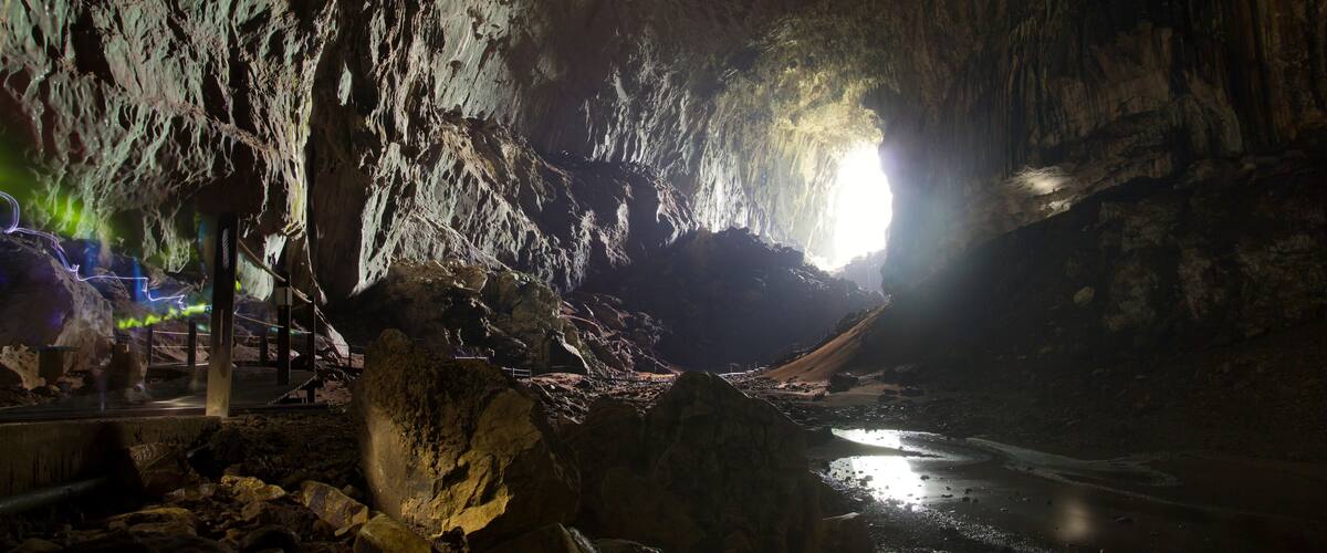 A cave with stalactites and a stream.