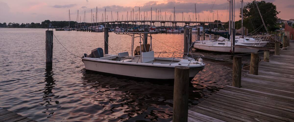 A marina with boats docked at wooden piers during sunset.