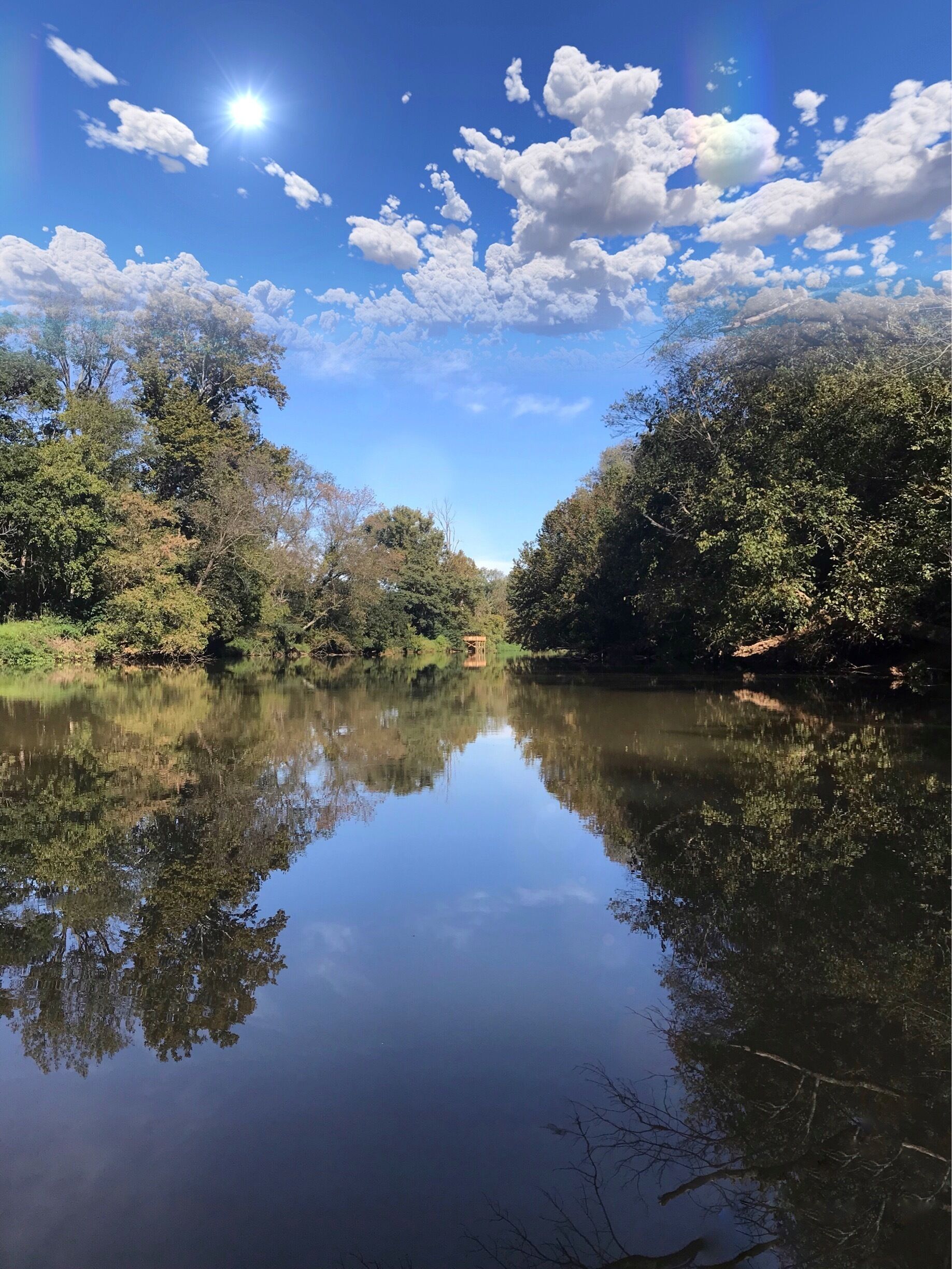 A calm river reflecting trees and sky.