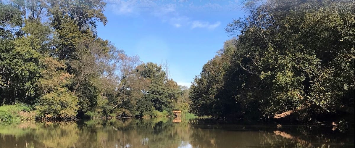A calm river reflecting trees and sky.