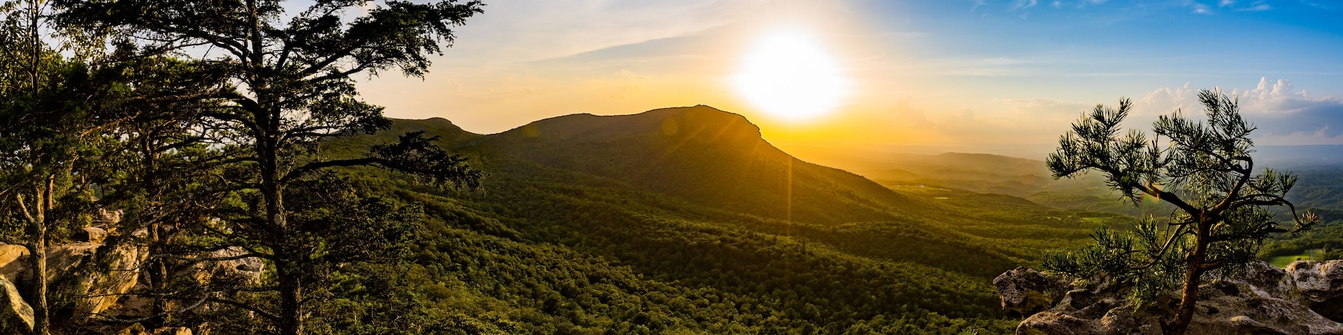 A mountainous landscape with a sunlit peak and dense forest.