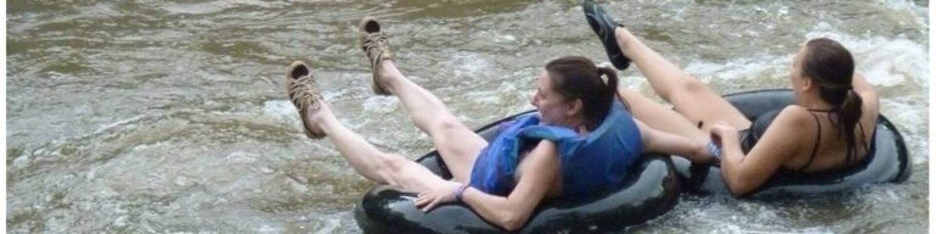 Two people on a raft in a river with rocks.