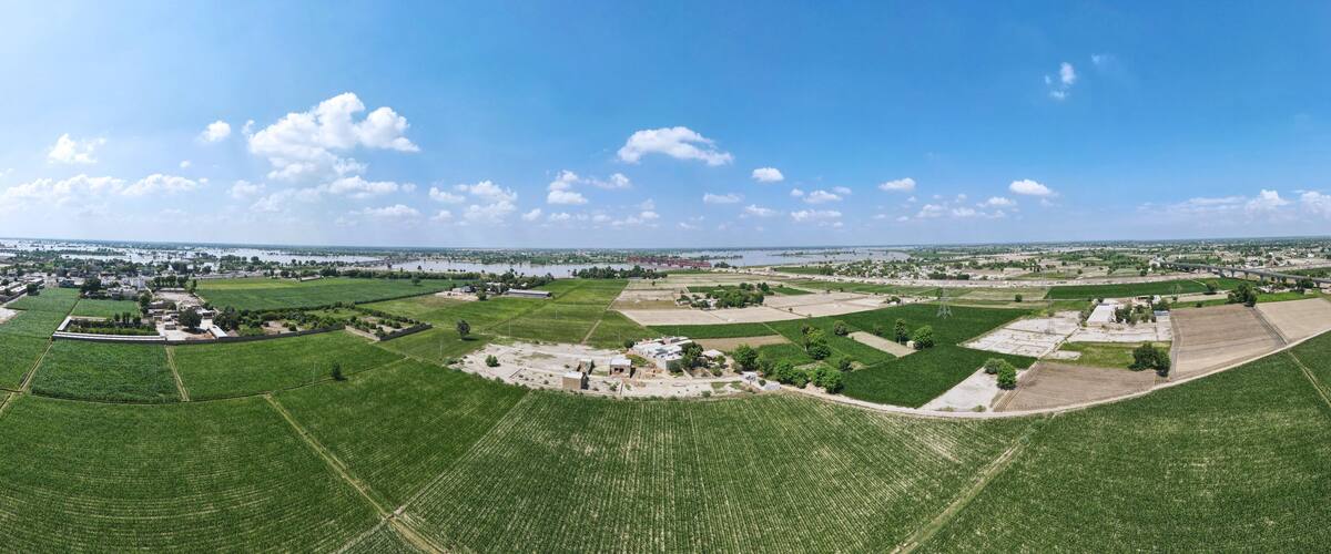 An aerial view of a rural landscape with fields, a small settlement, and a river in the distance.