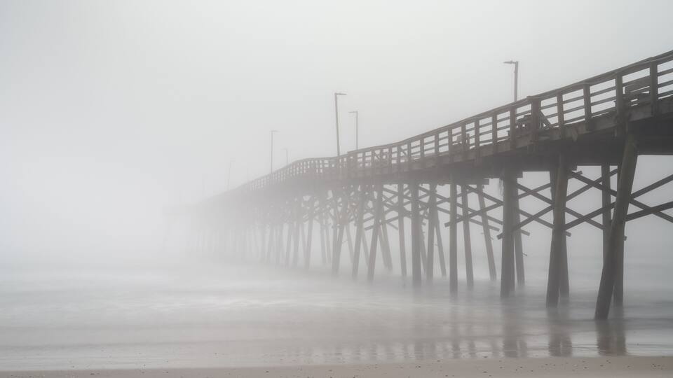 A foggy pier extending into the water.