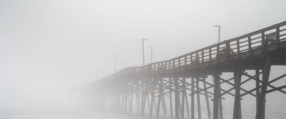A foggy pier extending into the water.