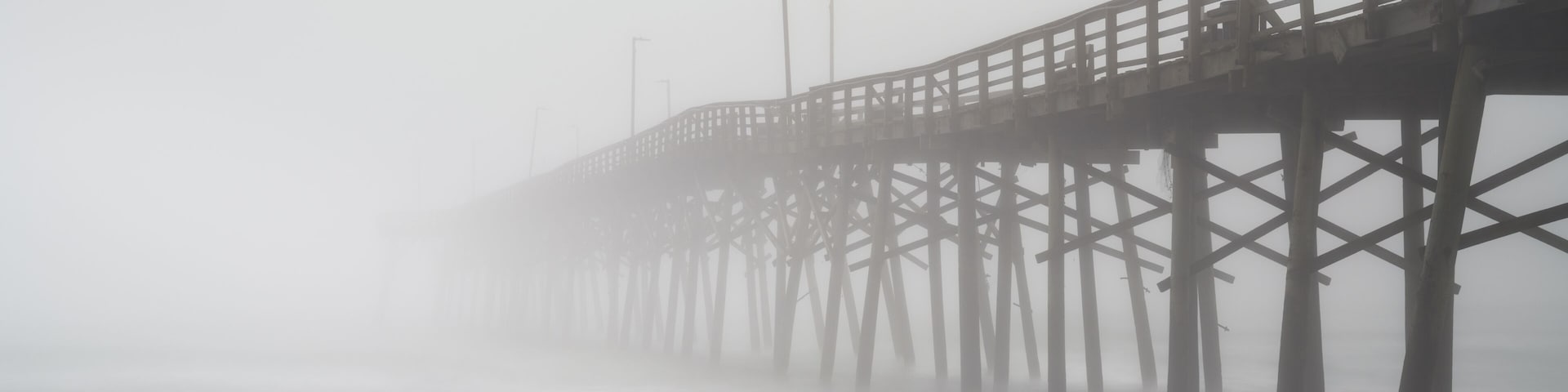 A foggy pier extending into the water.