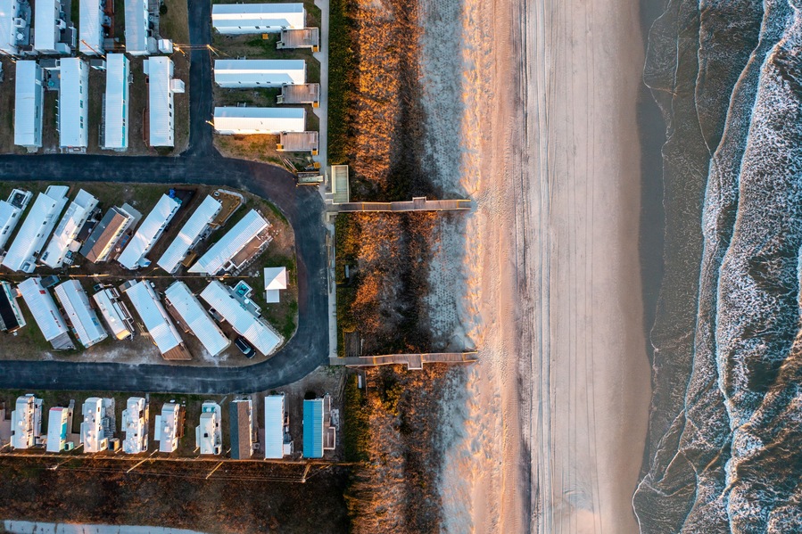Vista aérea de una zona industrial costera con almacenes, un puente y una playa.