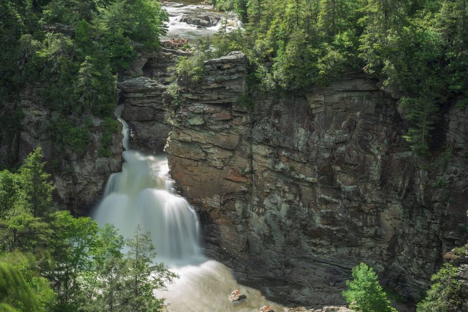 A waterfall cascading down a rocky cliff surrounded by dense forest.