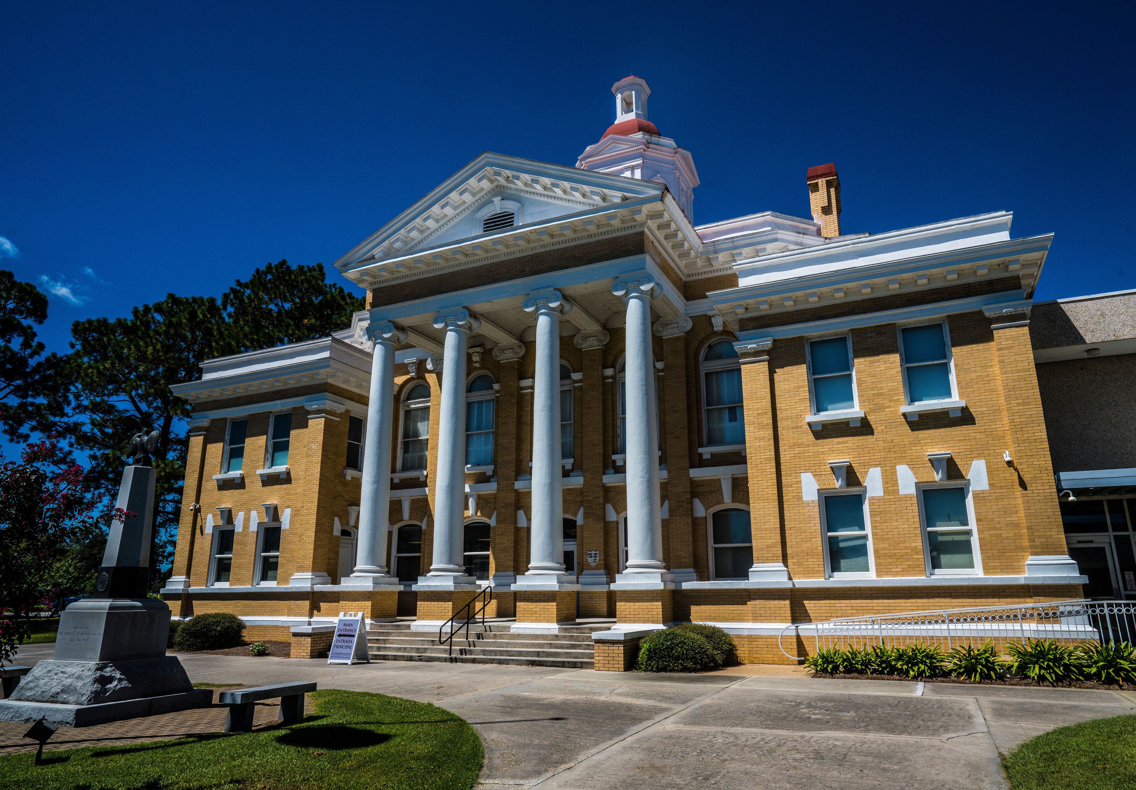 A large brick building with white columns and a red dome.