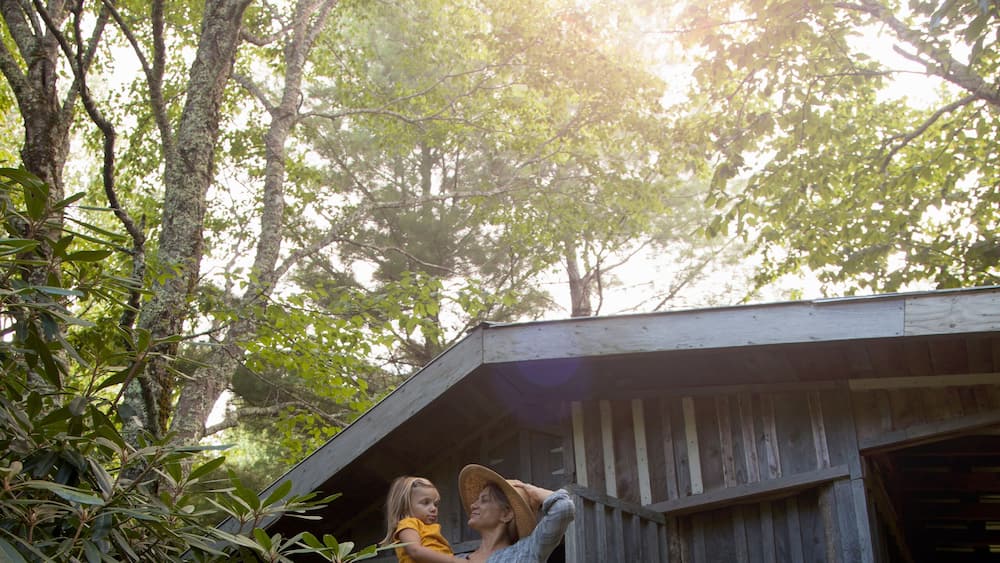 Mother and daughter standing outside wooden cabin