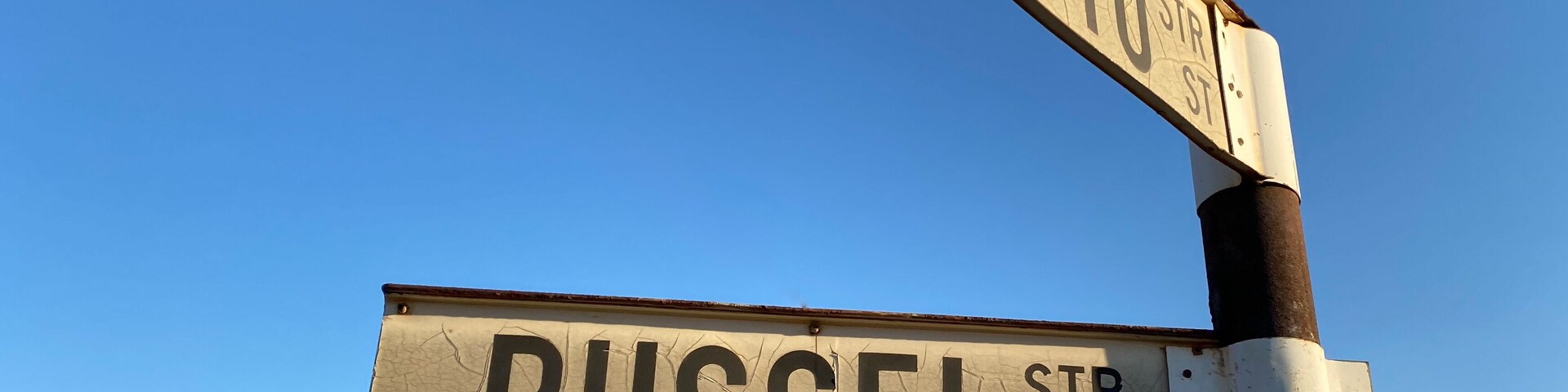 Señales de calle que indican 'OTTO ST' y 'RUSSEL STR' contra un cielo azul despejado.