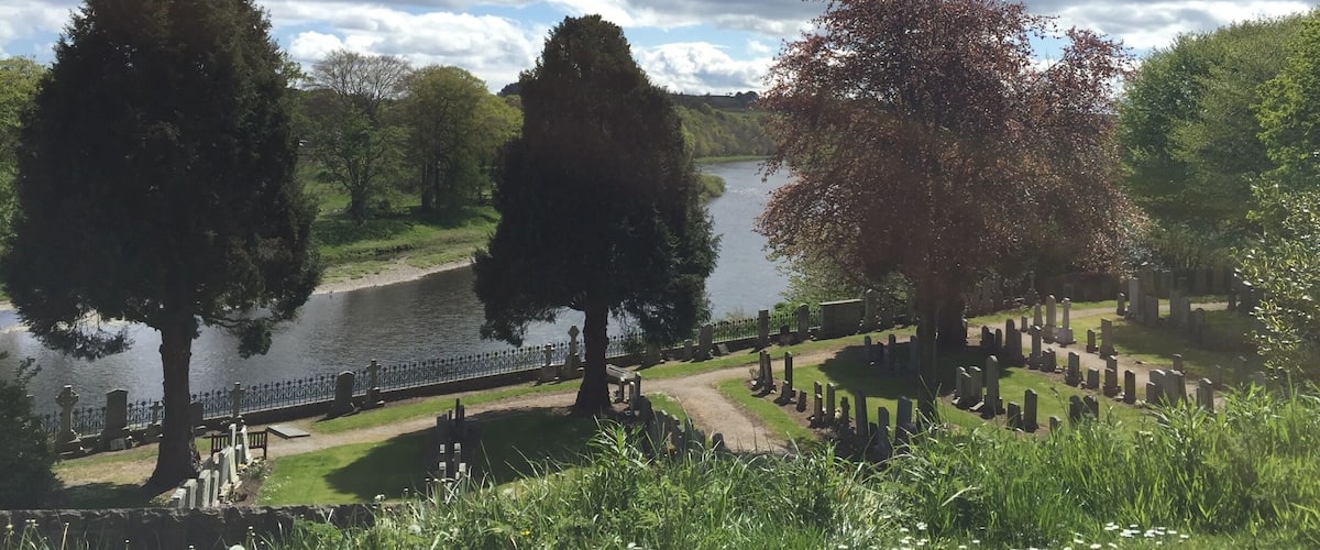 A cemetery with a lake, trees, and a cloudy sky.