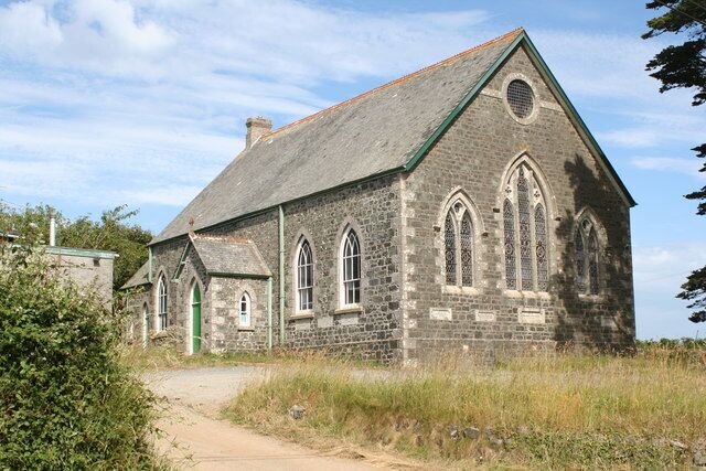A stone church with a green door and arched windows.