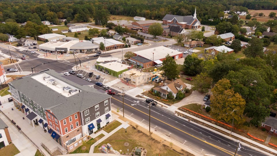 An aerial view of a town with a church, a large commercial building, and residential areas.