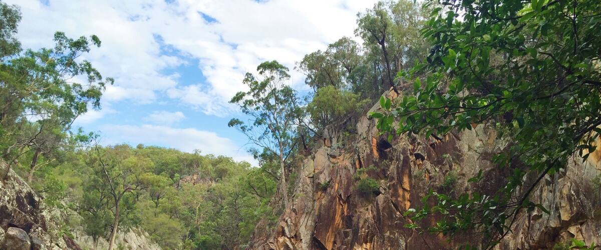 A serene river surrounded by rocky cliffs and lush greenery.
