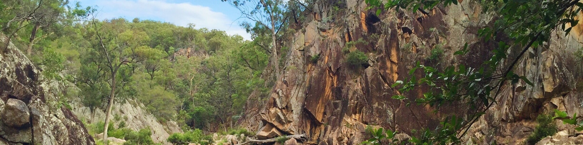 A serene river surrounded by rocky cliffs and lush greenery.