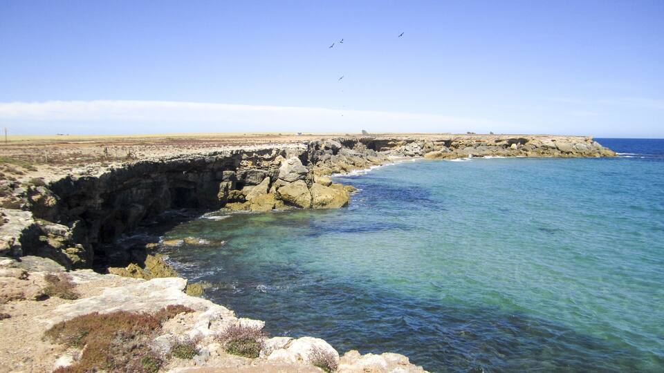 A coastal landscape with rocky cliffs and clear blue waters.