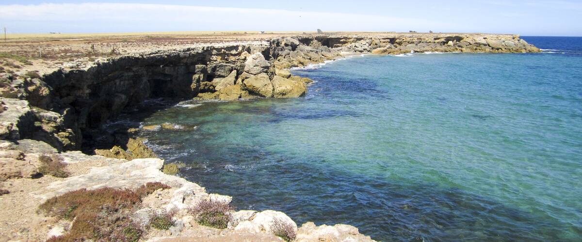 A coastal landscape with rocky cliffs and clear blue waters.