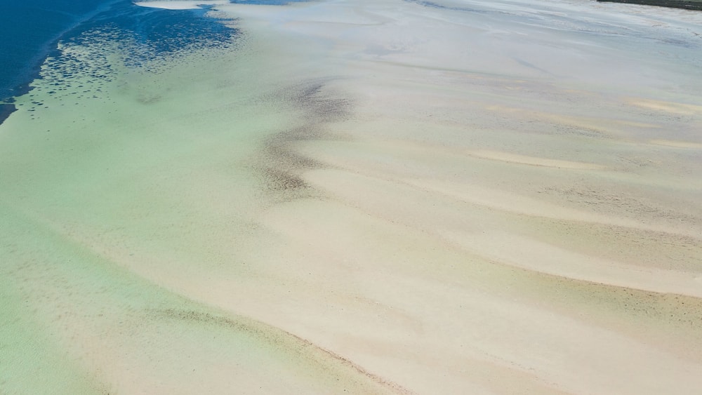 Ein weiter Sandstrand mit klarem, blauem Wasser und einer fernen Küstenlinie.