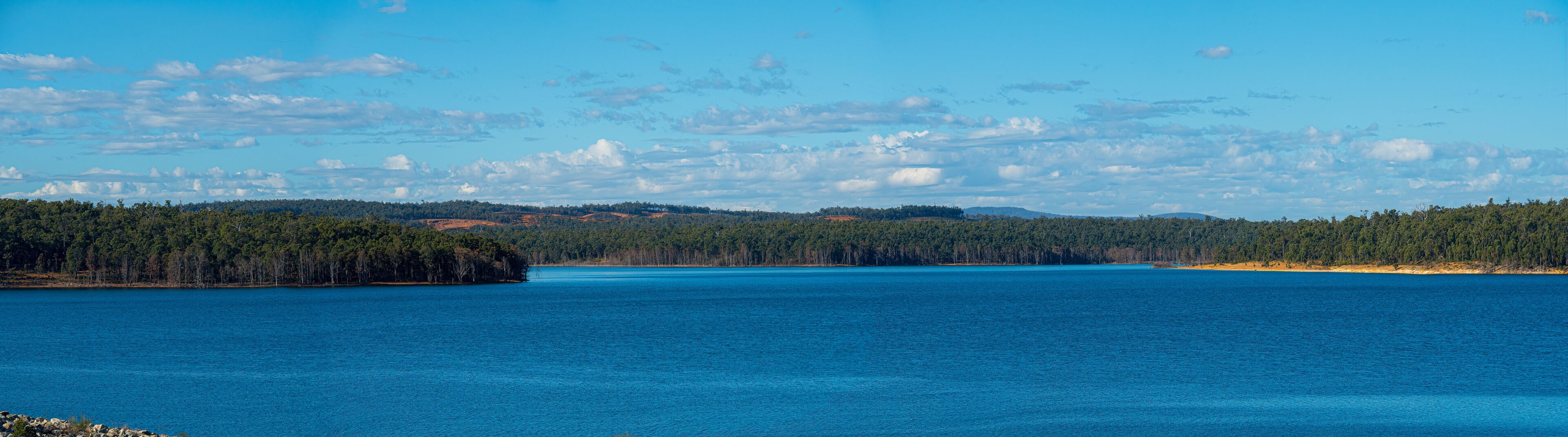 A large body of water surrounded by dense forests and distant hills.