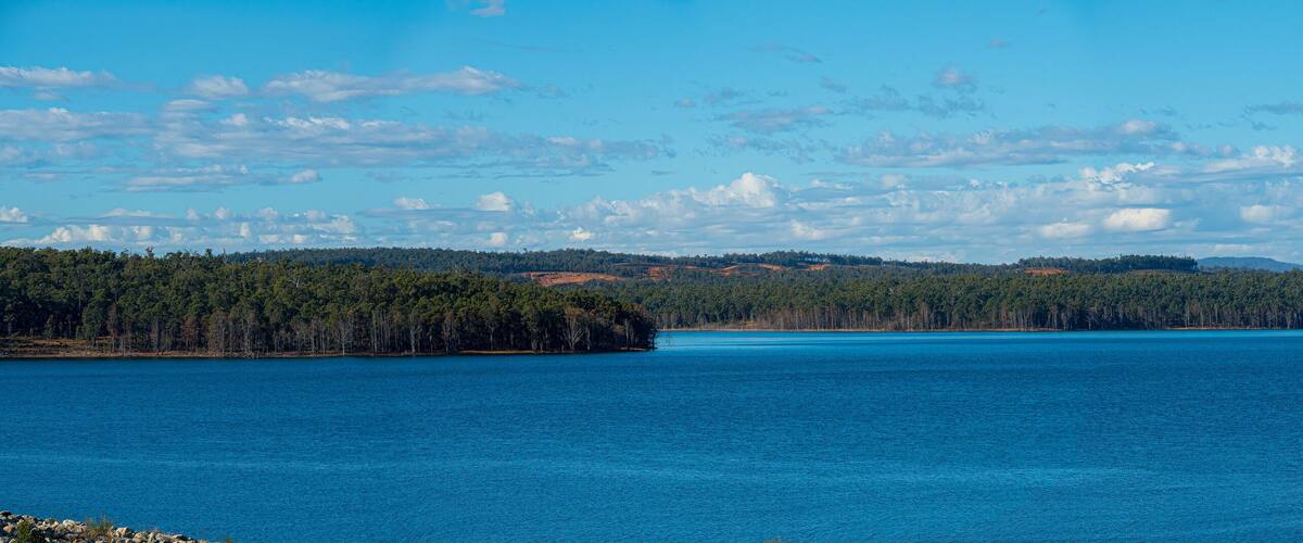 A large body of water surrounded by dense forests and distant hills.