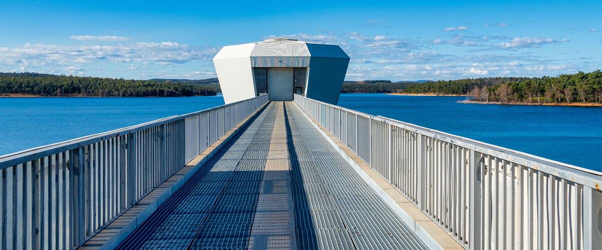 A bridge with a metal walkway leading to a white building with a large garage door.
