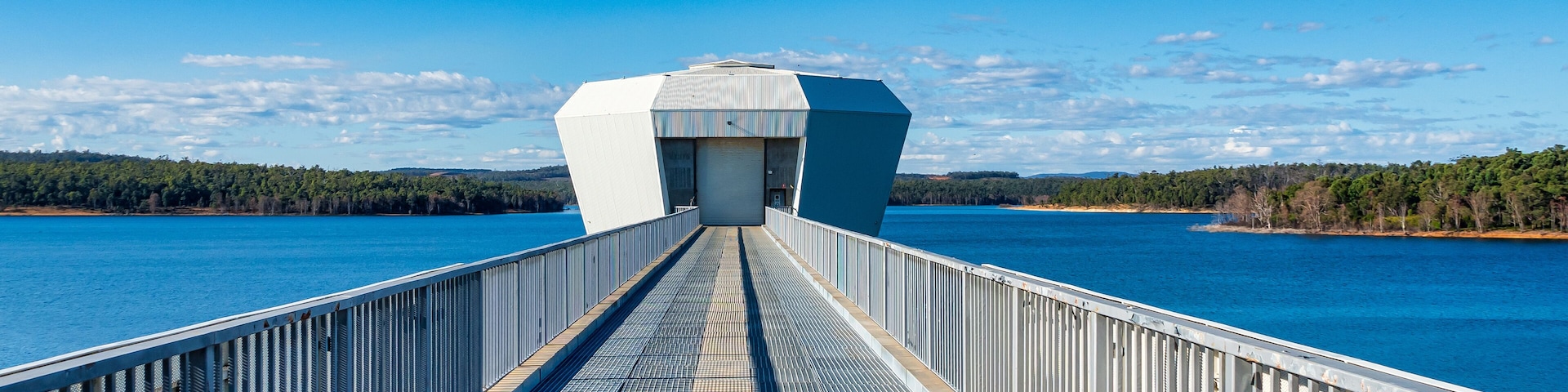 Eine Brücke mit einem Metallgeländer, das zu einem weißen Gebäude mit einer großen Garagentür führt.