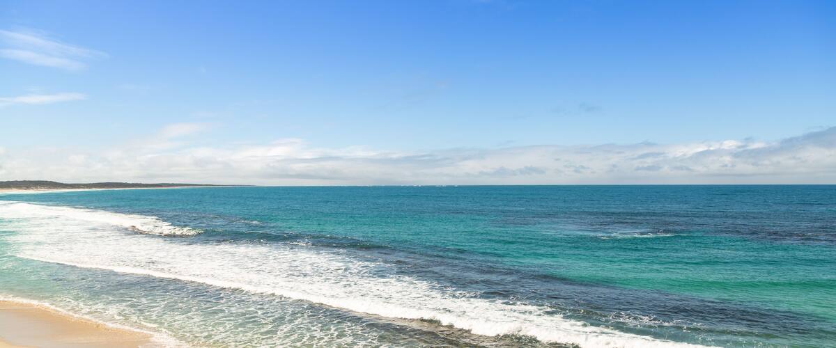 A beach with turquoise waters and a clear sky.