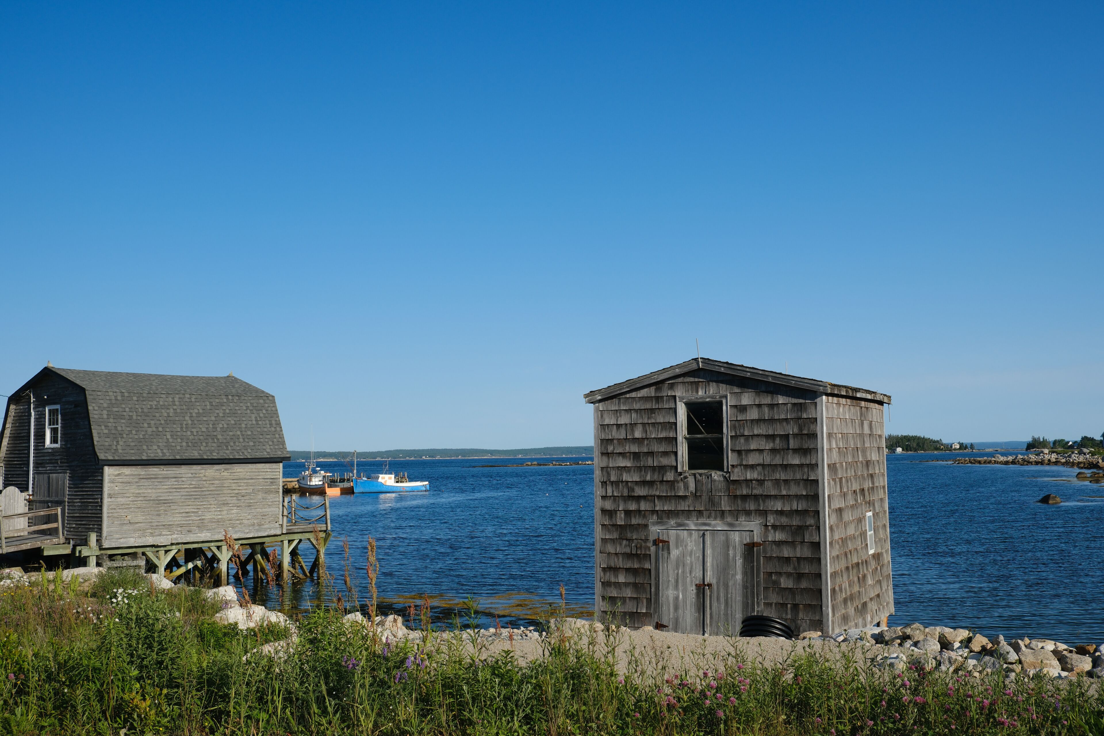 Weathered gray clapboard fishing shacks on a typical bay on a summer day in Nova Scotia's southern shores