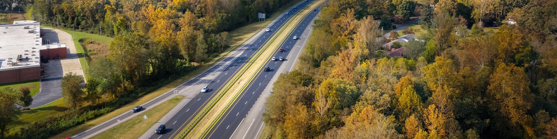 A highway surrounded by autumn-colored trees and mountains.