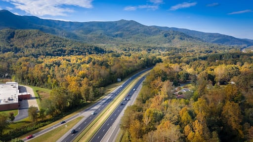 Una autopista rodeada de árboles y montañas de colores otoñales.