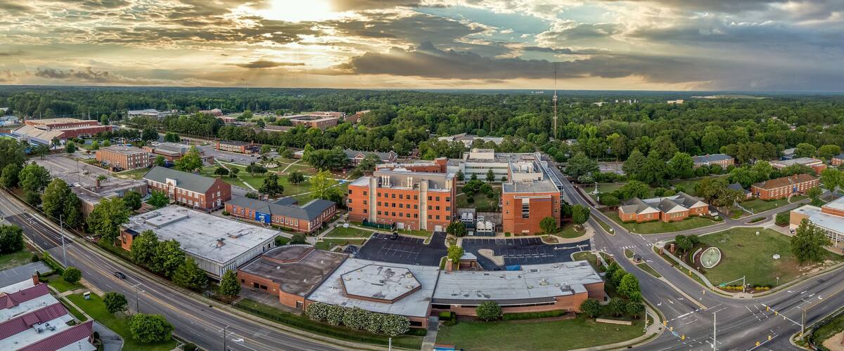 An aerial view of a university campus with multiple buildings, roads, and surrounding greenery.