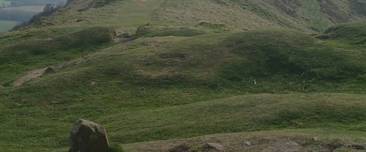A grassy hill with a path leading to a summit.