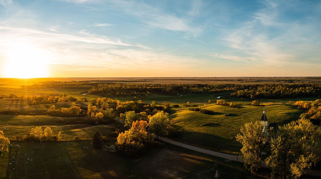 Aerial panorama of a sunset over the gentle rolling hills of the Great Plains with trees in their autumn colors in North Dakota.