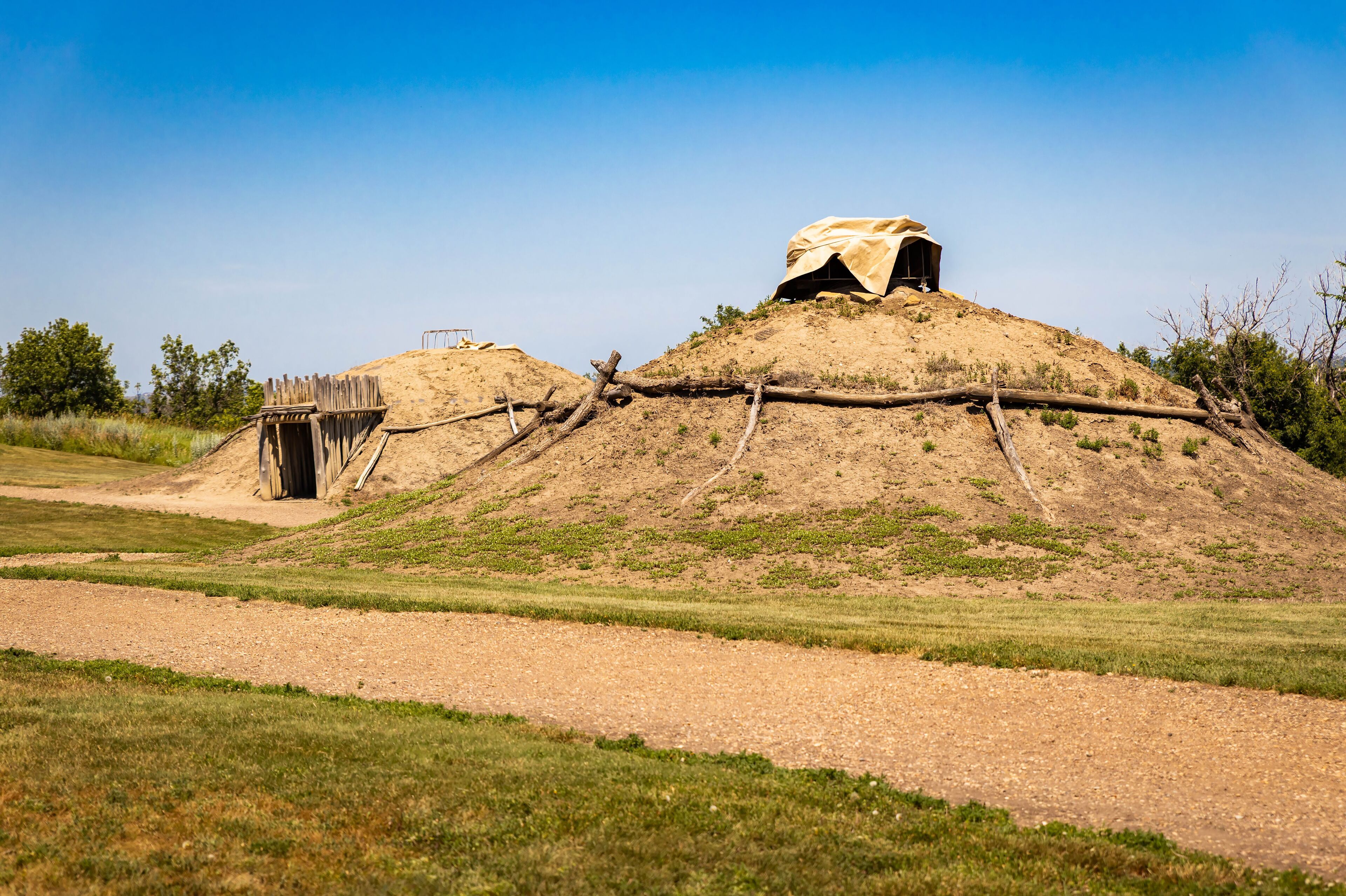 A mound with a covered structure and a wooden bridge.