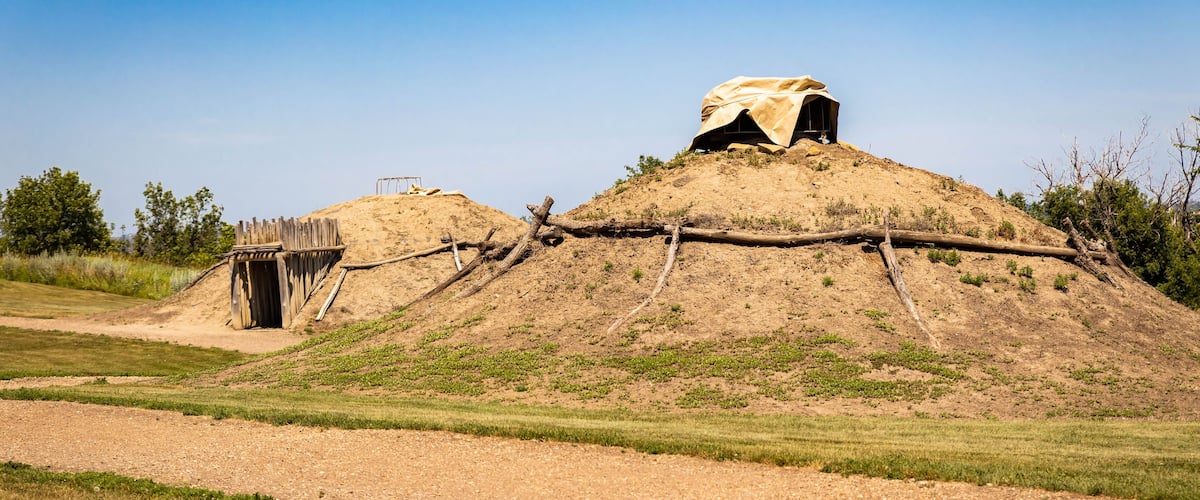 A mound with a covered structure and a wooden bridge.