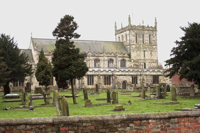 A historic church with a tall tower and a cemetery in front.